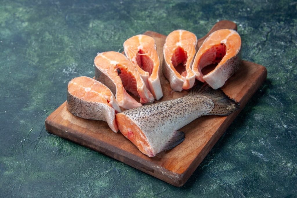 side view fresh raw fishes brown wooden cutting board dark mix colors table with free space krupnyj razmer 1 Выбор правильных мясных продуктов для сырого рациона кошек и собак - Блог SUPERPET